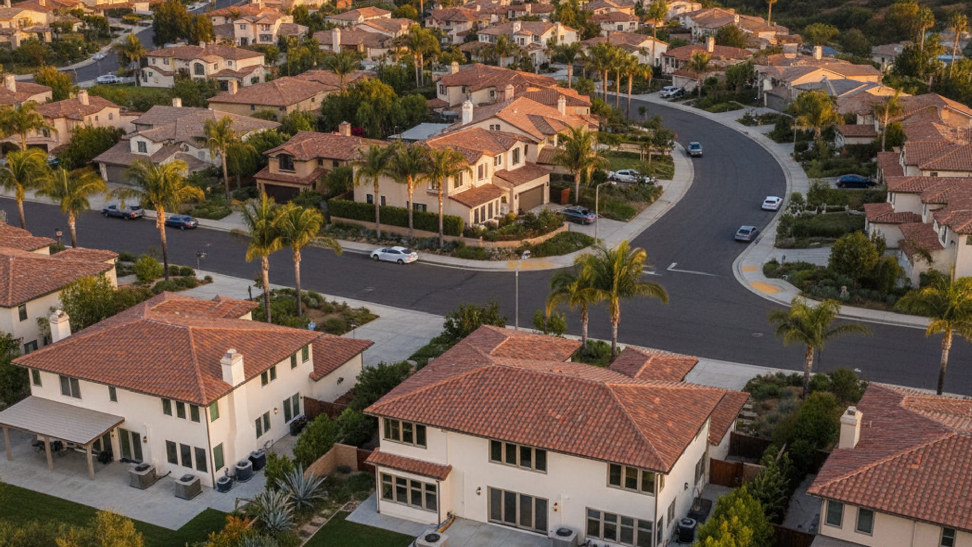 Aerial view of a San Diego County residential neighborhood with stucco homes and outdoor AC units visible in side yards at golden hour